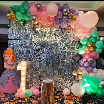 A popular choice for first birthdays, this princess-themed party features a sparkling silver shimmer wall backdrop. It's decorated with a 'Happy Birthday' neon sign, a light-up marquee number '1', and a beautiful pastel and metallic balloon garland.
