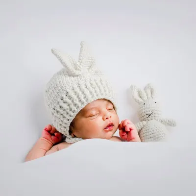 Our popular bunny theme is perfect for a cute and cozy newborn shoot. The knitted hat and matching bunny toy add a whimsical touch while the baby sleeps peacefully on a soft white background.