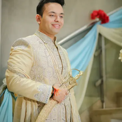 A handsome portrait of the groom on his wedding day. Dressed in a traditional sherwani, he looks happy and ready for the ceremony to begin.