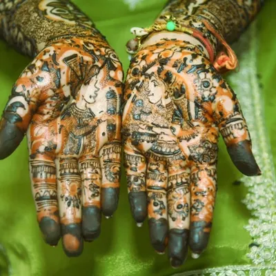 The beauty of bridal mehendi is in the details. This close-up shows the rich color and intricate patterns, featuring portraits of the bride and groom.