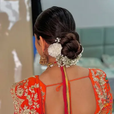 A classic bridal bun adorned with a combination of white flowers and baby's breath. This is a timeless and elegant choice for any bride.