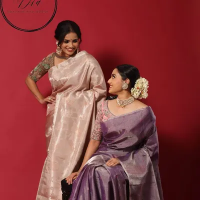A beautiful shot from a campaign, showcasing elegant makeup on two models in traditional tissue silk sarees. The looks are soft, complementary, and highlight a timeless South Indian aesthetic.