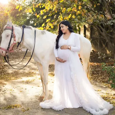 A quiet moment between a mother-to-be and a beautiful white horse. We style these outdoor maternity shoots to feel like a dream, using one of our flowing white gowns to complete the look.
