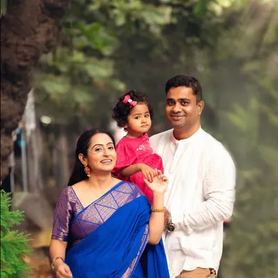 A beautiful family portrait taken outdoors with a touch of sunlight. The traditional outfits and natural setting create a perfect blend of culture and candid love.