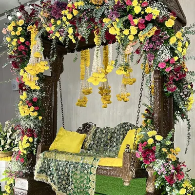 A stunning Haldi swing setup, overflowing with colorful flowers. We used a traditional wooden swing and decorated it with a mix of yellow, pink, and red blooms, along with hanging floral strings for a festive look.