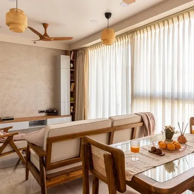 A complete view of the Japandi-style living and dining area, where teak wood furniture, rattan pendants, and sheer curtains come together to create a harmonious and light-filled environment.