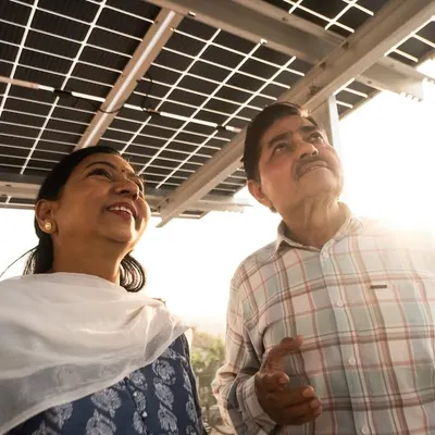 A couple admiring their new rooftop solar installation as the sun sets. We are proud to have helped thousands of families like them switch to clean energy and secure a brighter future.