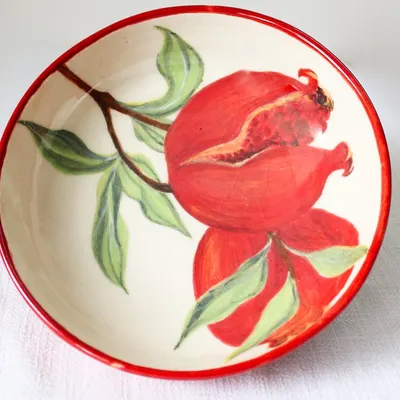 The 'Pomegranate Bowl' seen from a different angle, highlighting the rich red of the fruit and the delicate green leaves. This piece is fully food-safe, making it perfect for serving.