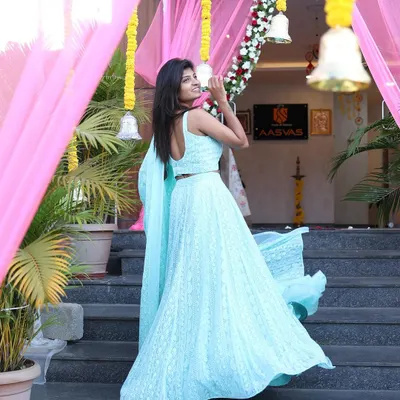 An apparel shoot for a designer studio, featuring a beautiful light blue lehenga. The movement in the skirt and the elegant backdrop of the entrance create a welcoming and aspirational fashion photograph.