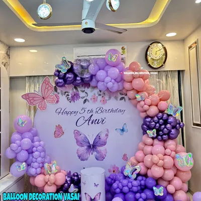 Anvi's 5th birthday with a beautiful butterfly theme. This setup features a round backdrop with a personalized message, surrounded by a stunning arch of purple and pink balloons.