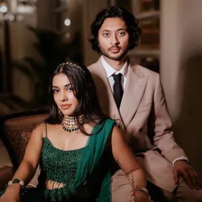 A modern and chic couple portrait. The bride's evening look is glamorous and edgy, with defined eyes and glowing skin that contrasts beautifully with the dark, moody lighting.