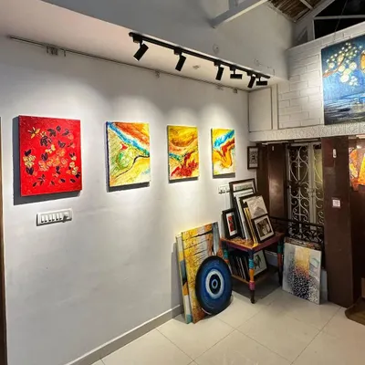 A view of our gallery's main wall, showcasing a variety of artworks under professional track lighting, with stacks of more canvases ready for collectors to explore.
