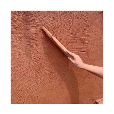 The wooden "thappi" tool against a finished wall, showing the distinctive cross-hatch texture it creates. This is the signature of the traditional Rajasthani lime plastering technique.