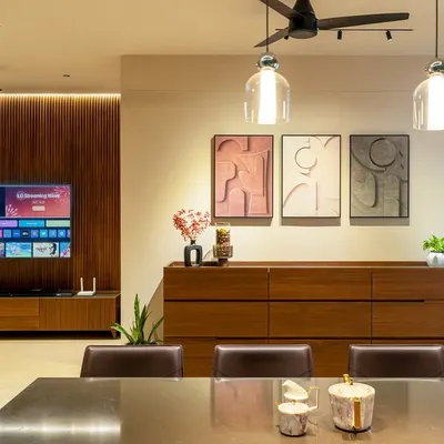 The dining and living area of the Humaize Apartment, where a wood-paneled feature wall houses the TV. A custom sideboard and contemporary art create a sophisticated yet functional space for the family.