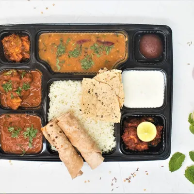 Our complete non-veg North Indian thali, packed and ready for delivery. This meal box includes two chicken curries, homestyle dal, jeera rice, soft phulkas, papad, curd, pickle, and a gulab jamun for dessert.