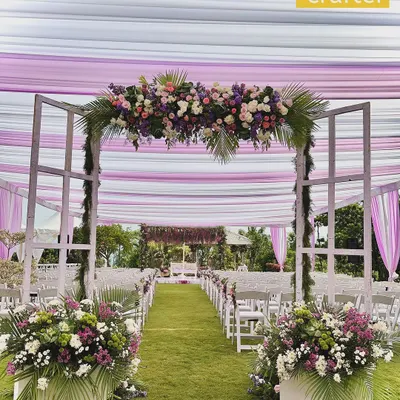 A dreamy garden wedding aisle. We used a white and lilac draped canopy, a floral archway, and lush arrangements to create a breathtaking path for the bride to walk down.