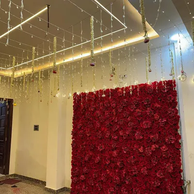 A magnificent red rose flower wall, perfect as a photo backdrop for a wedding, engagement, or any glamorous event. The hanging floral strings from the ceiling add an extra layer of detail.