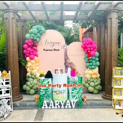 This outdoor jungle theme for Aaryav's first birthday shows how I can integrate elaborate setups into natural surroundings. The decor features vibrant balloon garlands, a giraffe cutout, and themed pedestals, all framed by a beautiful garden structure.