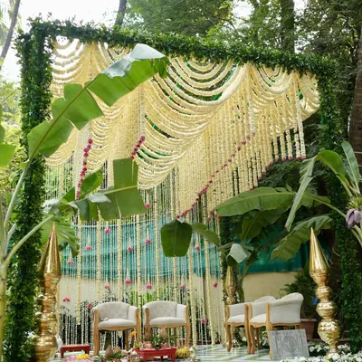 A dreamy, minimal mandap design perfect for an intimate garden wedding. We created a breathtaking curtain of tuberose garlands framed by lush greenery and banana leaves, with elegant seating for the couple.
