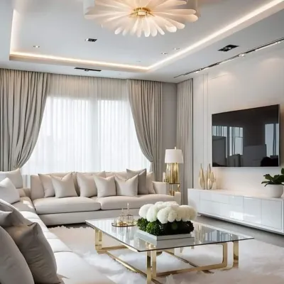 This living room design emphasizes serene elegance with a neutral color palette of cream and beige. A large L-shaped sofa offers plush comfort, while the gold-accented glass coffee table and a unique floral-inspired ceiling light add a touch of glamour.