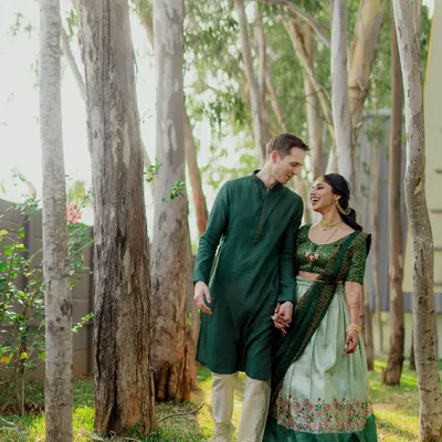 A beautiful portrait of a multicultural couple enjoying a walk in the woods. We love capturing the blend of traditions, like this groom's classic kurta paired with his bride's elegant lehenga.