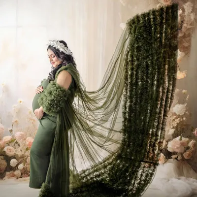 A dramatic portrait featuring a stunning green gown with a long, textured train. The pose is designed to show off the incredible detail of the dress and create a powerful, statuesque look.