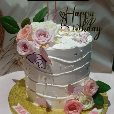 A beautiful floral cake for a 10th birthday. This tall cake features a textured buttercream finish, pink and white sugar roses, and delicate wafer paper butterflies.