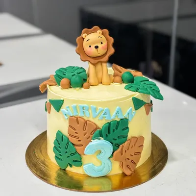 A sweet jungle-themed cake for Nirvaan's 3rd birthday. This design features a cute, handmade fondant lion topper, monstera leaves, and a personalized name banner.