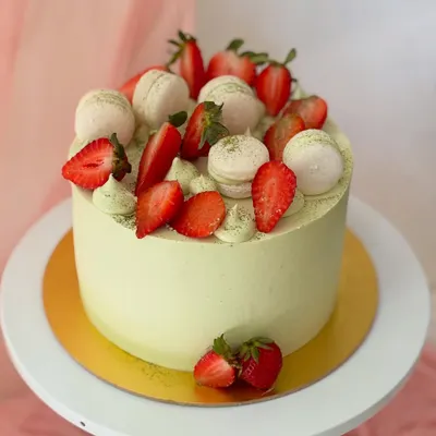 A beautiful matcha and strawberry cake. The light green matcha-infused buttercream is perfectly complemented by a generous topping of fresh, juicy strawberries and macarons.