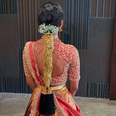 A detailed back view of a traditional South Indian bridal braid, adorned with a golden accessory and fresh baby's breath.