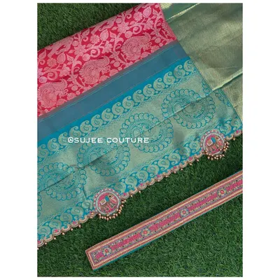 A flat lay showcasing the details of a custom saree border and matching hip belt. The design features embroidered elephant motifs inside decorative medallions, finished with small bead tassels.