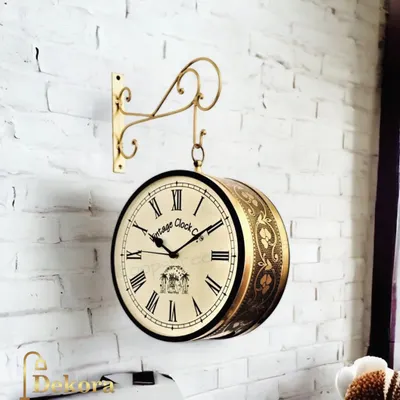 A vintage-look station clock with a golden finish and an ornate wall bracket. This double-sided clock is a nostalgic and stylish piece, perfect for hallways or open-plan offices.