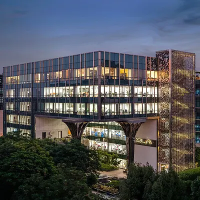 A wide-angle evening shot of the Jindal Stainless Steel Office, showcasing the building's impressive scale, illuminated interiors, and the unique faceted steel-clad columns we designed for the entrance.