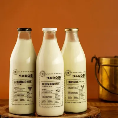 A clean product shot of Barosi's range of A2 milk. The warm, simple background and rustic wooden tray highlight the farm-fresh quality of the products, perfect for a website's product page.