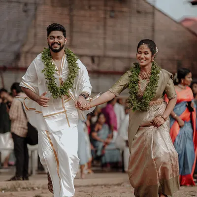 A classic shot of a newly married Kerala couple, hand in hand, walking away from their temple ceremony. Their happy faces and traditional attire tell a story of new beginnings.