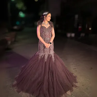 This deep wine-colored fish-cut gown with feather details and intricate beadwork is the definition of glamour. It features a long, dramatic trail for a red-carpet-worthy entrance.