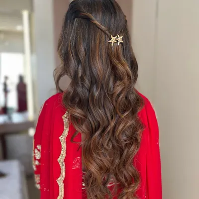 The perfect finishing touch. This hairstyle features soft, romantic waves with a simple twist and delicate star-shaped pins, complementing a soft glam makeup look beautifully.