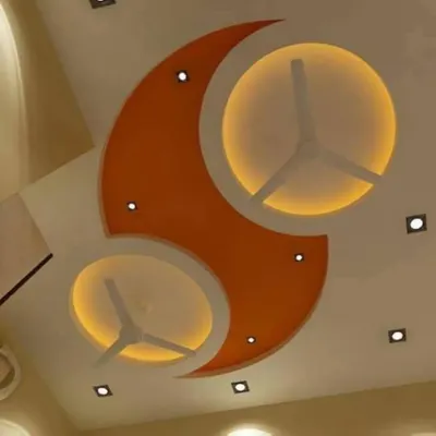 A creative design for a large room with two fans. The ceiling features a large orange crescent shape that elegantly incorporates both fans into backlit circular cutouts.