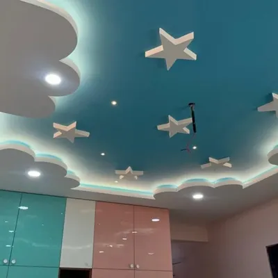 The centerpiece of this kids' room is the custom false ceiling, designed to look like a dreamy sky with clouds and stars, complete with integrated LED lighting.
