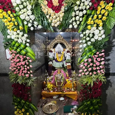 My work includes detailed floral adornment for temple deities. Here, a floral arch made of roses and chrysanthemums frames the idol, enhancing the sacred atmosphere.