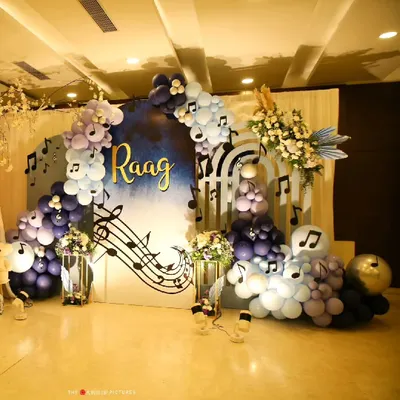 For a naming ceremony celebrating a baby named 'Raag', I designed this music-themed backdrop. It features a cascade of purple and blue balloons, musical notes, and a custom name sign to create a harmonious and joyful setting.