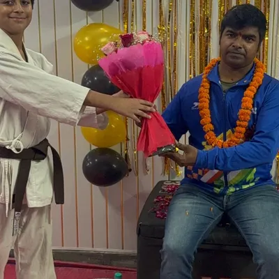 A student with a brown belt respectfully presenting flowers on Teacher's Day, showing the strong bond we build.