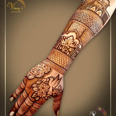 A delicate back-hand design featuring a bird surrounded by flowers. The pattern extends up the arm with architectural and floral bands.
