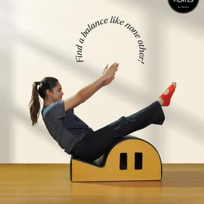 Finding balance is a key principle of Pilates. This image shows a client performing a teaser on the spine corrector, a move that requires immense core control and balance.