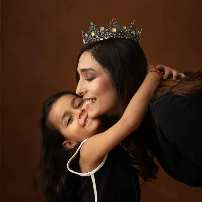 A mother-to-be, wearing a crown, shares a sweet hug with her daughter. This maternity portrait beautifully captures the bond between them before the new baby arrives.