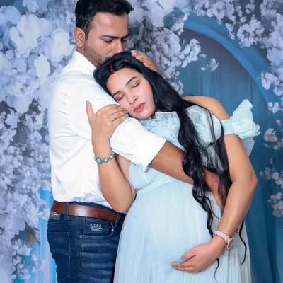 We focus on capturing the genuine emotion between you. This image shows a tender embrace, with the mother-to-be feeling safe and loved in her partner's arms, set against a soft, floral studio backdrop.