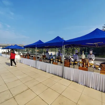 This is the catering setup for an Indigo Airlines corporate event. We provided a long line of buffet stations under protective blue canopies, ensuring a professional and organized food service area for the guests.