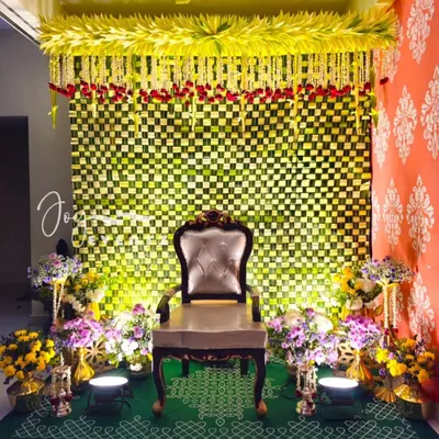 An elaborate and traditional decoration for a half saree ceremony. This setup features a woven banana leaf backdrop, a canopy of jasmine and rose petals, and a beautiful kolam design on the floor.