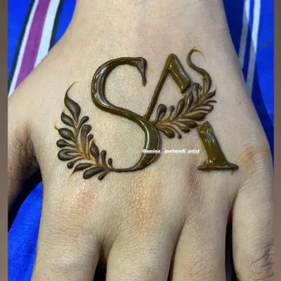 A simple and elegant way to personalize your mehendi with initials. Here, the letters 'SA' are drawn in a beautiful script and adorned with delicate leaves.