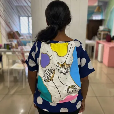 A participant modeling her beautifully hand-painted abstract backpack. Our backpack painting activity lets you create a stylish and necessary travel essential.